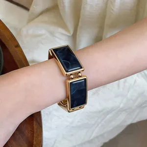 Detailweergave van een vintage rechthoekige blauwe marmeren schakelarmband op pols.