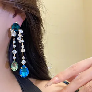 Detailansicht von langen Hängeohrringen mit leuchtend blauen und grünen Tropfenkristallen