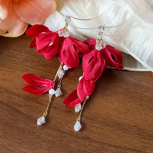 Close-up of elegant red fabric flower tassel earrings with white pearls and crystals