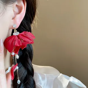 Detailed close-up of red fabric flower earrings with pearl tassels and crystals