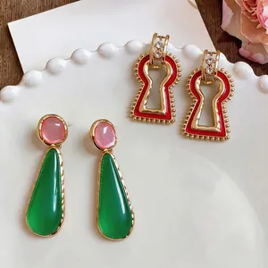 Elegant resin waterdrop and red keyhole geometric earrings displayed on a white plate