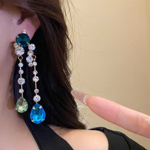 Detailaufnahme von luxuriösen goldfarbenen Ohrhängern mit leuchtend blauen Kristalltropfen