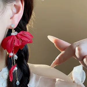 Macro view of elegant red fabric flower earrings with delicate pearl and crystal tassels