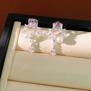 Gros plan d'élégantes boucles d'oreilles en argent avec cristal rose et perle chic