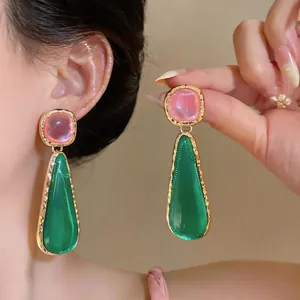 Close-up of pink and green resin drop earrings with gold textured frames