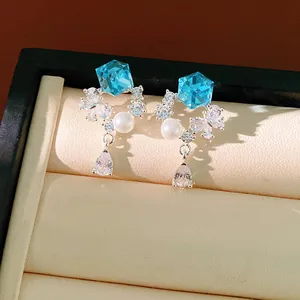 Détail de boucles d'oreilles en argent avec cristaux hexagonaux bleus et perles