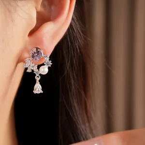 Gros plan de boucles d'oreilles en argent avec zircon violet et perle pendante