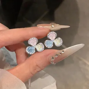 Detailed view of three-petal flower stud earrings with pastel stone inlay and CZ border.