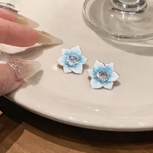 Macro view of blue and white gradient flower stud earrings featuring a sparkling center zircon