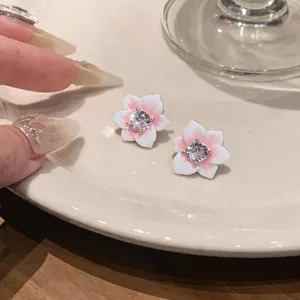 Close-up detail showing elegant pink and white flower stud earrings with zirconia center