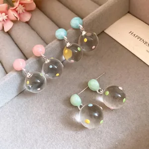 Elegant silver needle dangle earrings featuring clear ice-like polka dot globe pendants
