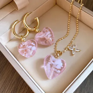 Detailaufnahme von rosa Herz-Ohrringen und Halskette in einer Geschenkbox.
