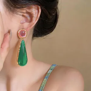 Close-up detail of resin teardrop earrings in pink and green on model's ear