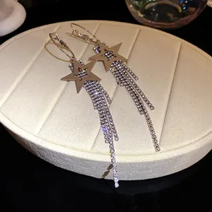 Close-up of silver-tone star earrings with sparkling rhinestone long tassels on a display