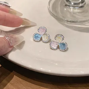 Close-up of elegant silver three-petal flower stud earrings with colorful zircon stones