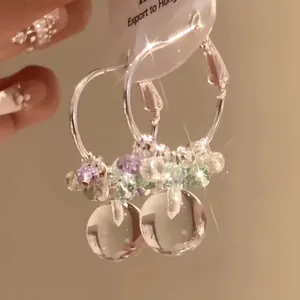 Detail shot of summer ice-clear colorful beaded hoop earrings with round pendants
