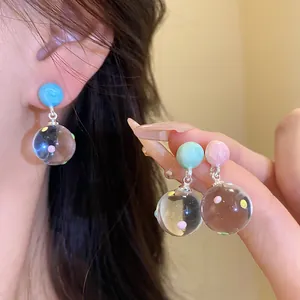 Close-up detail of ice-transparent ball pendant earrings with colorful polka dots