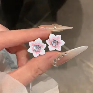 Close-up view of elegant pink and white flower stud earrings featuring a central zircon stone