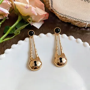 Detailed view of elegant gold-toned water drop earrings featuring a unique black keyhole design