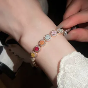 Close-up van kleurrijke ronde zirkonia armband om pols met elegant kanten mouwdetail.