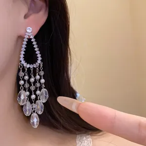 Detalle de elegantes pendientes de araña con circonitas, perlas y gotas de cristal.