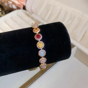 Detailopname van een 18k vergulde armband met kleurrijke ronde zirkoniasteentjes in halo.