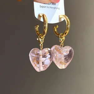 Nahaufnahme von eleganten rosa Kristallherz-Ohrringen mit goldenen Creolen-Details