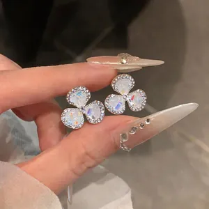 Macro detail of elegant flower stud earrings with iridescent centers and zircon edges.