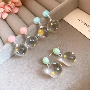 Detailed macro view of silver needle clear polka dot sphere pendant earrings set