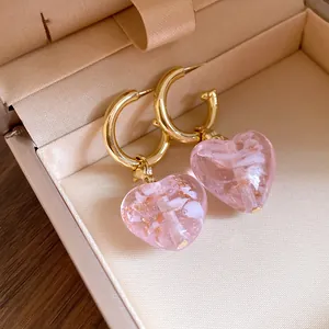 Nahaufnahme von eleganten rosa Kristall-Herz-Ohrhängern in einer luxuriösen Schmuckschatulle