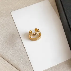 Macro view of French style gold double-layer ear cuff with quilted texture and smooth band.