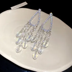 Vista detallada de gotas de cristal brillantes y perlas en elegantes pendientes largos colgantes