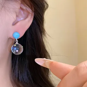 Close-up view of translucent ball drop earrings with colorful dots worn on a model's ear