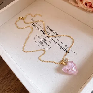Detailansicht des rosa Kristallherz-Anhängers mit Blumeneinlage an einer Goldperlenkette