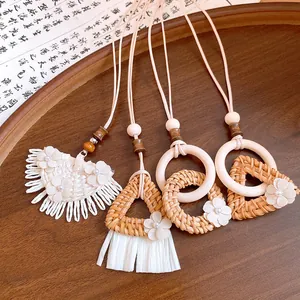 Close-up detail of various bohemian wood rattan necklaces with elegant white flower accents