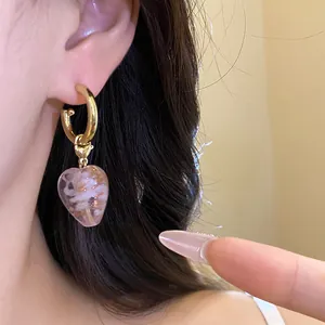 Detailaufnahme von Vintage-Ohrringen mit herzförmigen rosa Kristallanhängern und Blumen