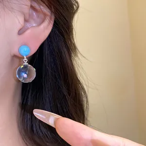 Close-up of blue stud earrings with transparent polka dot glass ball pendant