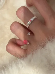 Dettaglio di un anello aperto con fragola e stella su sfondo di pelliccia bianca