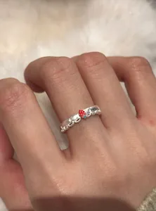 Dettaglio di un anello in pizzo argento con fragola e stelle indossato su un dito.