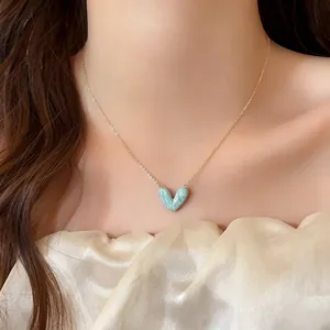 Nahaufnahme eines blau marmorierten Herzanhängers an einer zarten goldenen Kette
