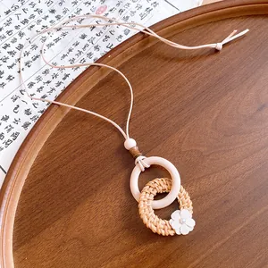 Detailed view of bohemian handmade wooden and woven rattan ring necklace with floral charm