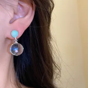 Detail view of silver needle drop earrings with clear polka dot sphere pendant