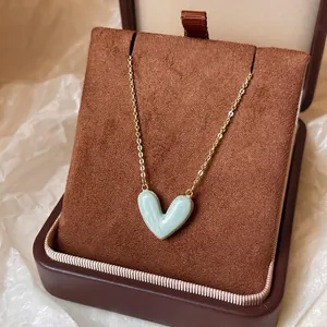 Detail einer hellblauen Herz-Halskette mit Marmor-Effekt in einer braunen Geschenkbox.