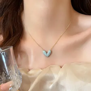 Nahaufnahme einer eleganten Halskette mit marmoriertem blauem Herzanhänger am Hals