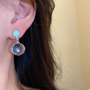 Elegant ice-clear glass ball drop earrings with colorful polka dots shown on ear