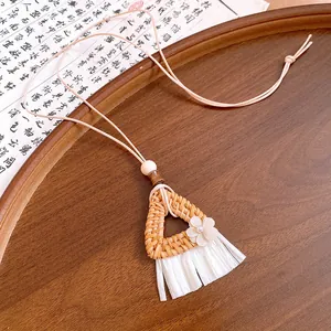 Detailed macro view of a bohemian style woven rattan triangle necklace with tassels.