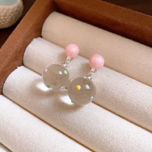 Close-up detail of ice-transparent polka dot glass ball drop earrings in a box