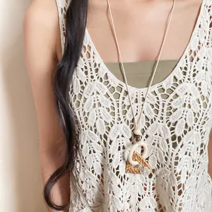 Detailed view of a bohemian woven wood pendant necklace on a crochet lace top.