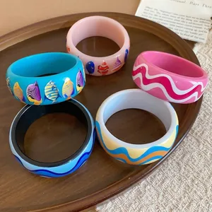 Colorful ocean-themed resin bangles featuring vibrant tropical fish and artistic wave patterns