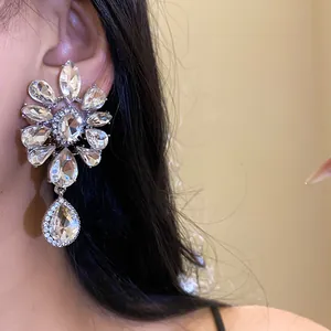 Detail of flower shaped rhinestone ear clip with teardrop pendant on model